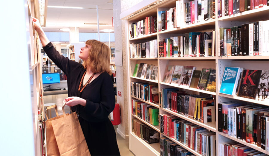 Bibliotekarie Maria Olsson packar en kasse till en låntagare. Bibliotekarie Maria Olsson packar en kasse till en låntagare.